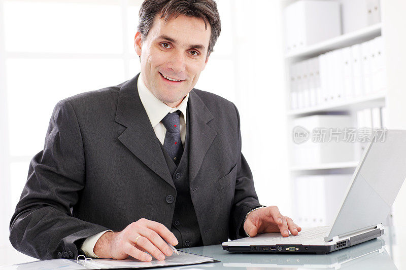 微笑的商人在笔记本电脑工作。