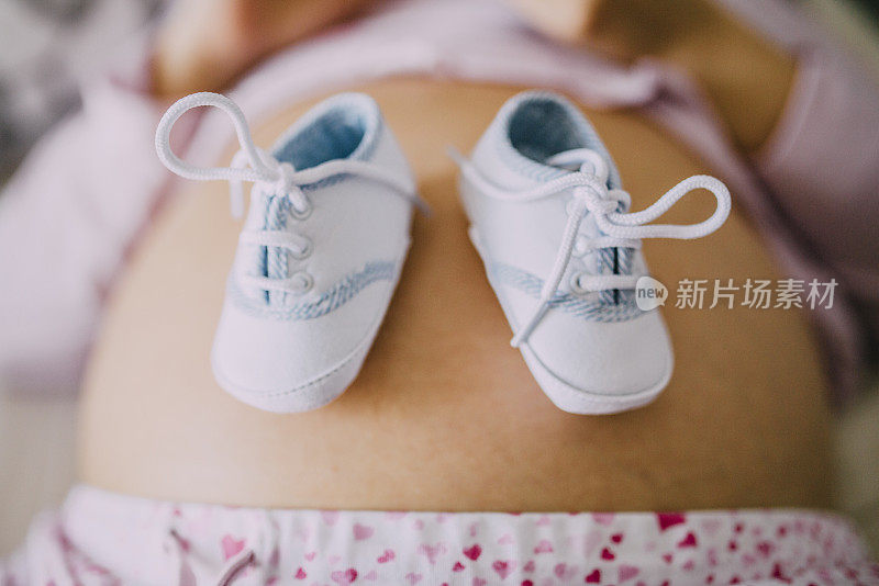 宝宝的鞋子放在怀孕的肚子上