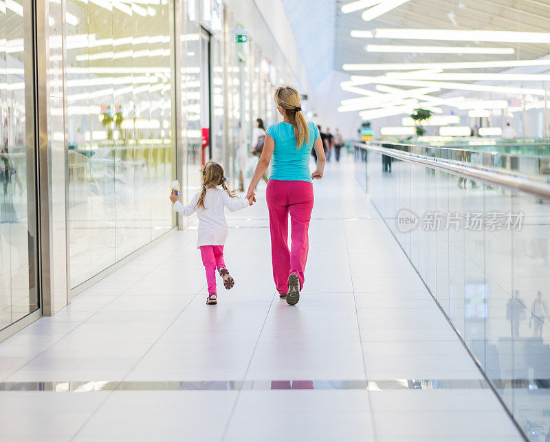 后视图的母亲和女儿享受在购物中心。