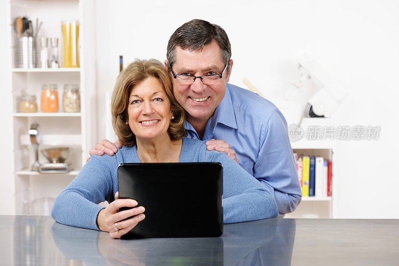 一对成熟的夫妇在厨房里使用平板电脑