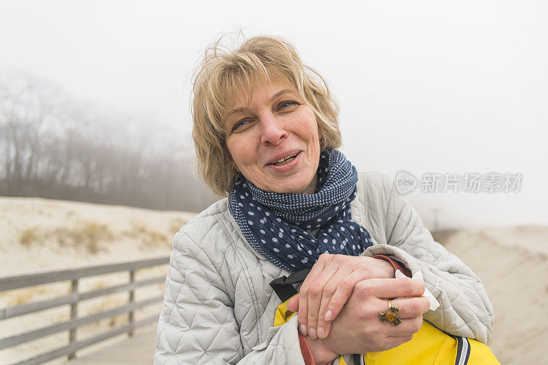 这是一个迷人的，快乐的，成熟的50岁女人在海滩上的肖像