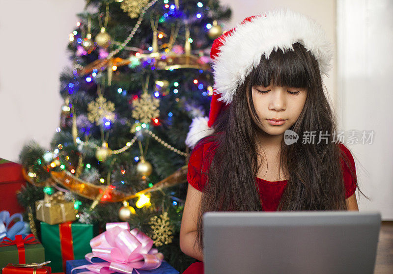 一个亚洲小女孩在用圣诞节收到的新笔记本电脑