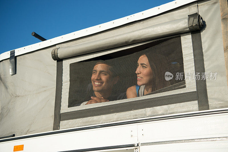 夏日里，一对年轻漂亮的夫妇坐在露营车里
