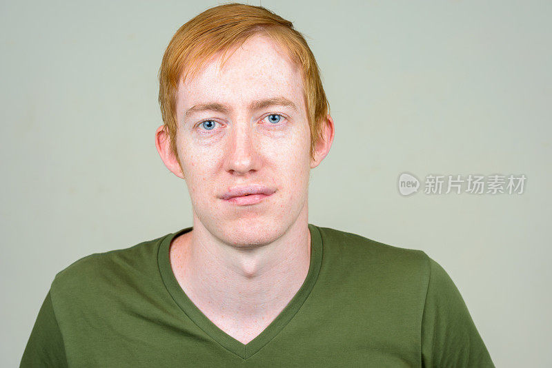 橙色头发的男人穿着绿色衬衫映衬着白色的背景