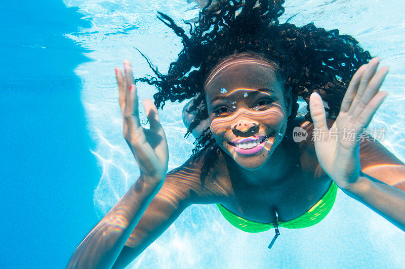 度假的黑人女孩在游泳池跳水