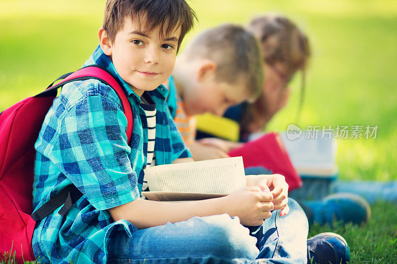孩子们背着背包坐在学校附近的公园里