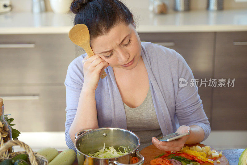 女人在厨房做饭(用智能手机)