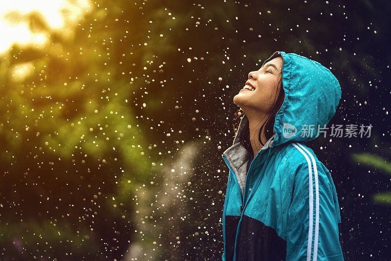 在户外穿雨衣的亚洲妇女。她是快乐的。