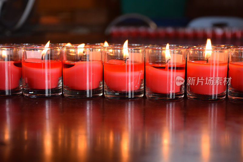 火光从红烛。木头桌上放着玻璃蜡烛。光线反射在木头上