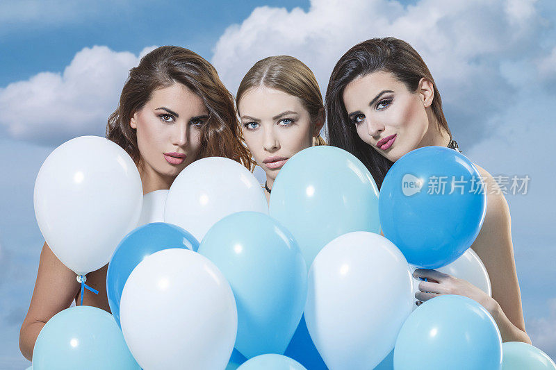 三个年轻女人拿着一堆氦气蓝色的气球顶着天空夏天的时尚