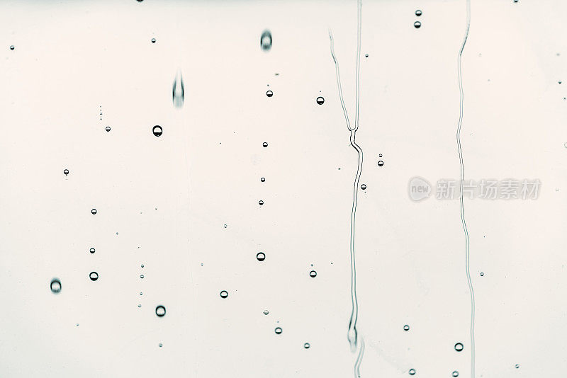 雨滴落在玻璃上流动的水，背景是黑色的颜色，选择性聚焦。