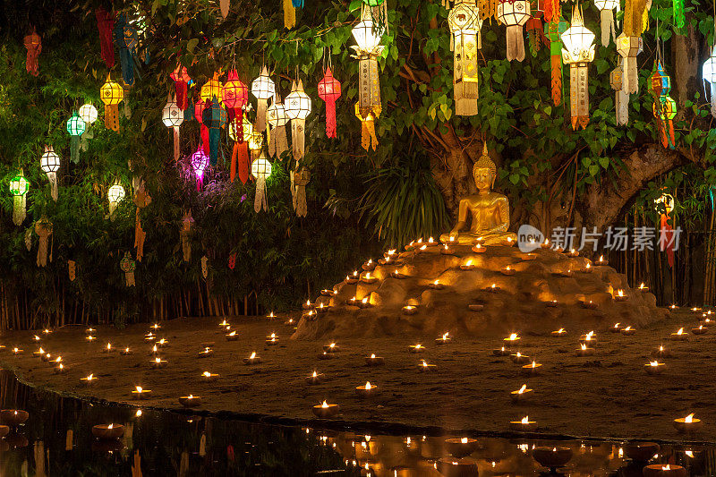佛像周围是蜡烛和五颜六色的灯笼。