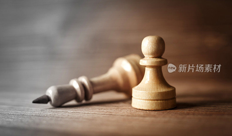 象棋的国王和卒设置在木制背景上。成功的领导和团队理念。象棋中兵胜王的概念