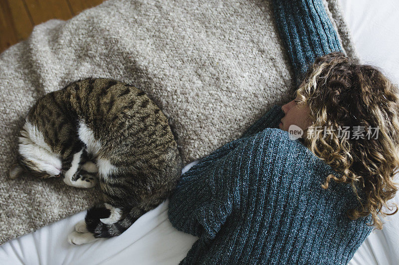 美丽的年轻女子和她的猫在床上