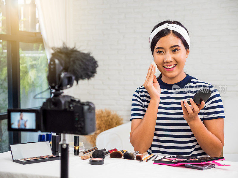 年轻的亚洲美容博主介绍化妆品和记录她的化妆教程视频到社交网络在家通过互联网