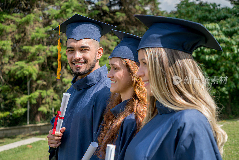 一个年轻人和他的同事们都拿着毕业证书，微笑着看着镜头
