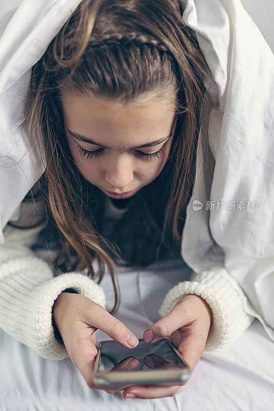 卧室里有手机的可爱小女孩