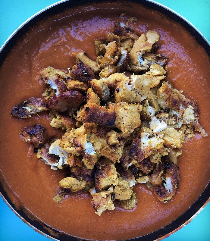 这是在煎锅里的印度黄油鸡块和酱汁，咖喱鸡和烤鸡胸肉的照片