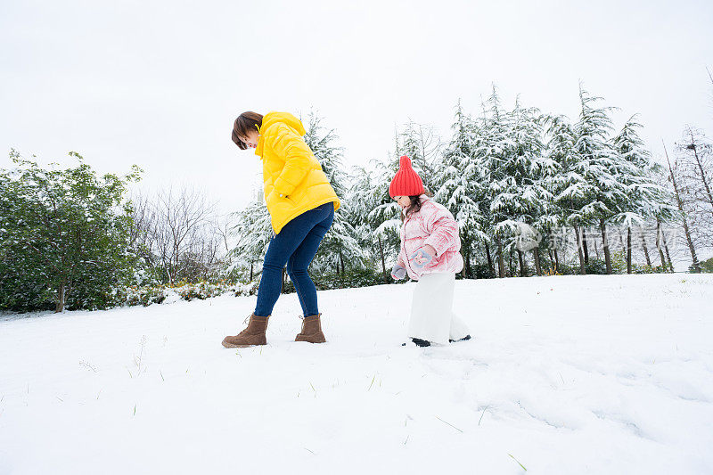 一个小女孩和妈妈在雪中玩耍