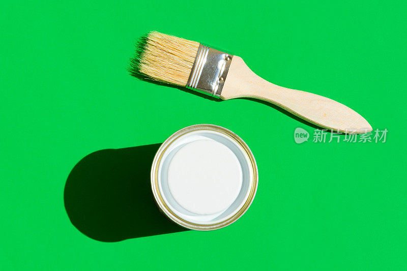 油漆刷与木柄罐清漆时髦的绿色背景。室内设计家居装修时尚理念。现代波普艺术风格，强烈的光线和强烈的阴影。海报占位符