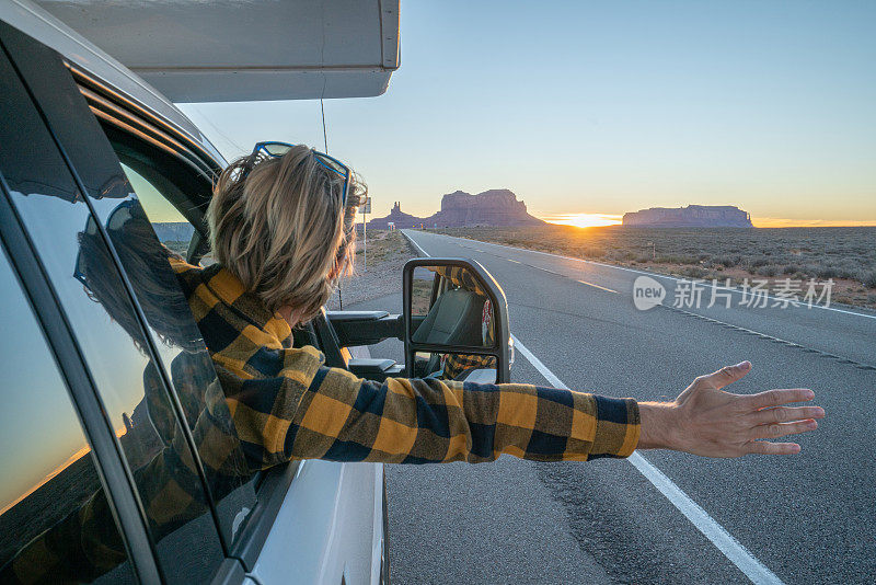 公路旅行概念;年轻人在房车里看着路，手臂伸出窗外;国家公园和大自然为探险做好了准备