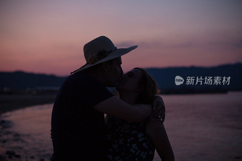 一对情侣在沙滩上接吻的剪影