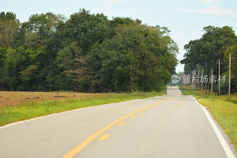 双车道的道路在起伏的地形通过森林地区与森林在框架的左边