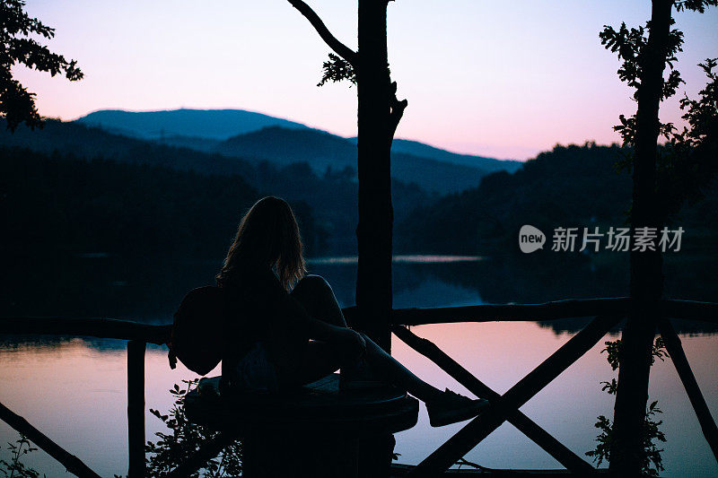 一个安详的女孩在欣赏日落时分的湖景