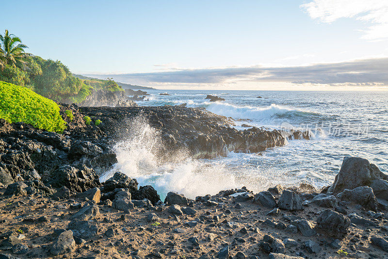 日出时的岩石海岸线，海浪拍打着夏威夷毛伊岛的悬崖