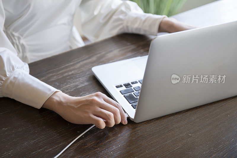 一个女人的手正在把电源线插入个人电脑的USB接口