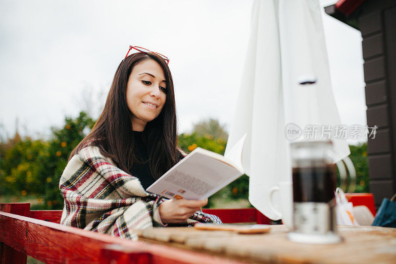 在阳台上喝咖啡看书的女人