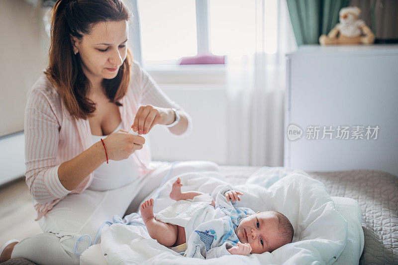 妈妈在卧室的床上给她的男婴换尿布