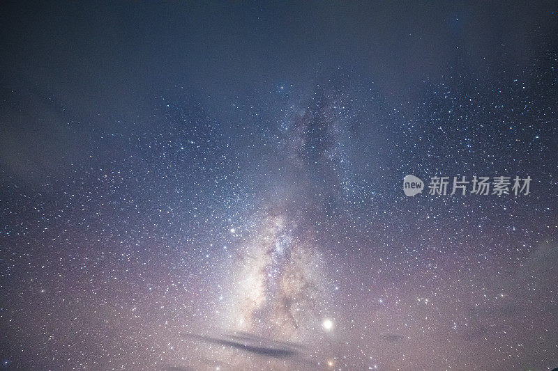 山上有银河和粉红的光。晚上多彩的景观。夏天的星空和山峦。美丽的宇宙。太空背景与星系。旅游的背景