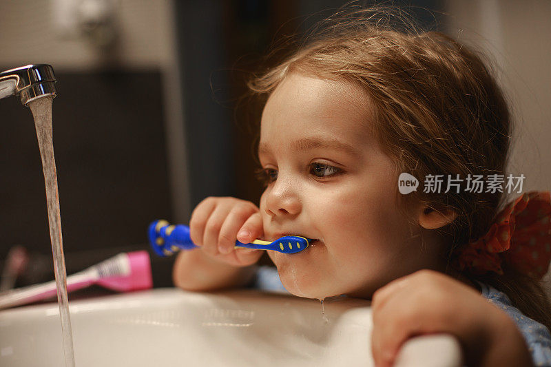 小女孩刷牙的时候水龙头开着浪费水