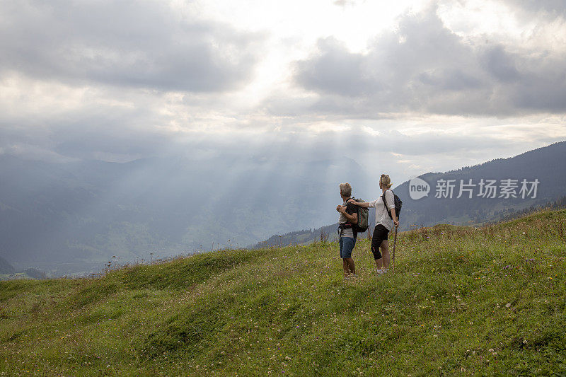 日出时分，一对成年夫妇徒步穿过高山草甸