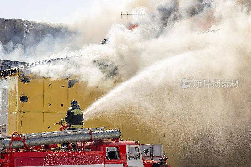 2020年8月5日俄罗斯秋明地区下涅瓦托夫斯克市。工业仓库失火。一名消防队员将一股水流引向着火的建筑物