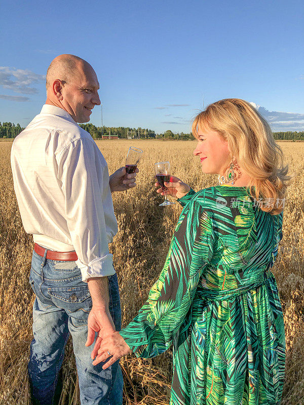 一男一女，一对白人夫妇在喝酒。庆祝结婚周年纪念日。在城外的燕麦地里野餐。