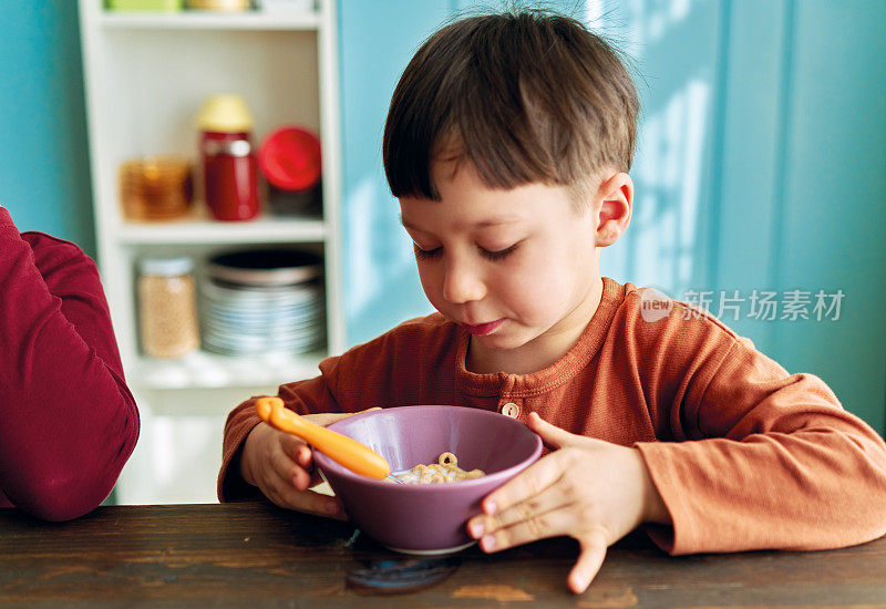 可爱的孩子们早餐吃玉米片和牛奶