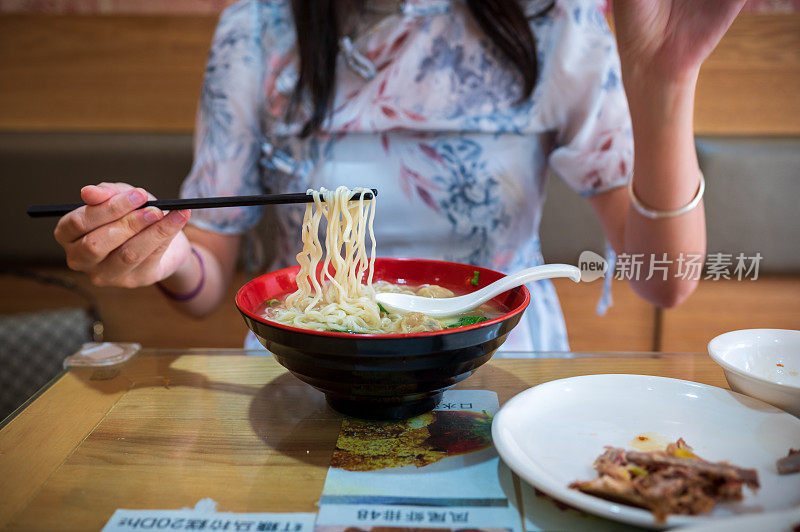 在餐馆用筷子吃馄饨面汤蔬菜餐的女人特写