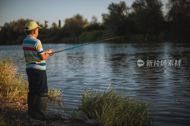 一个男孩在河边钓鱼