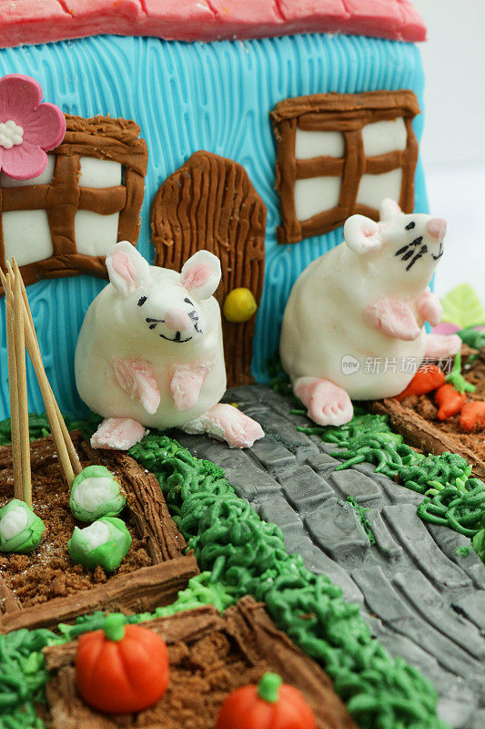 自制的图片，方糖白老鼠除了装饰蛋糕设计成小屋和花园的菜圃，黄油糖霜草与巧克力片和饼干屑土壤蔬菜种植花椰菜和胡萝卜，重点放在前景