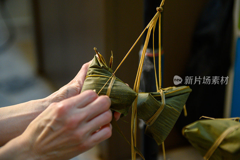 女人用手包粽子。端午节的传统食品