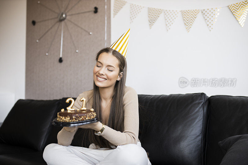 年轻漂亮的女人在家里用巧克力蛋糕庆祝她21岁的生日