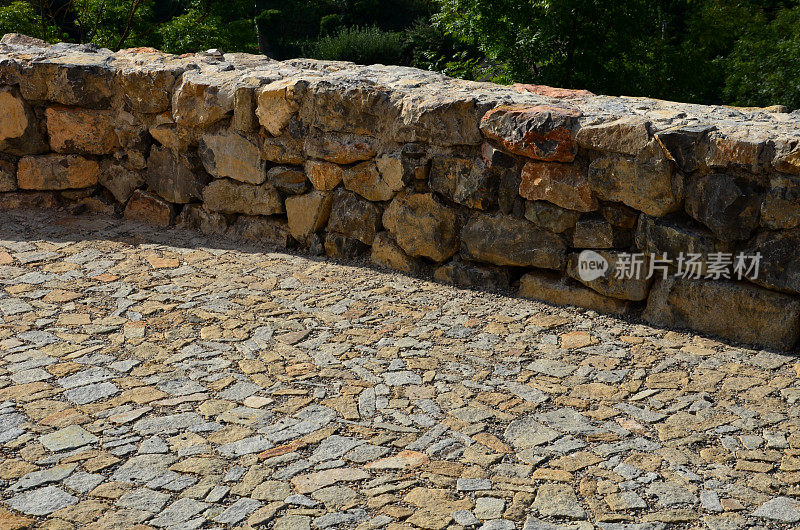 毛石与水泥砂浆结合的漂亮折叠挡土墙。褐色米黄色不规则石灰石。把斜坡保持在上面。排水管离墙。