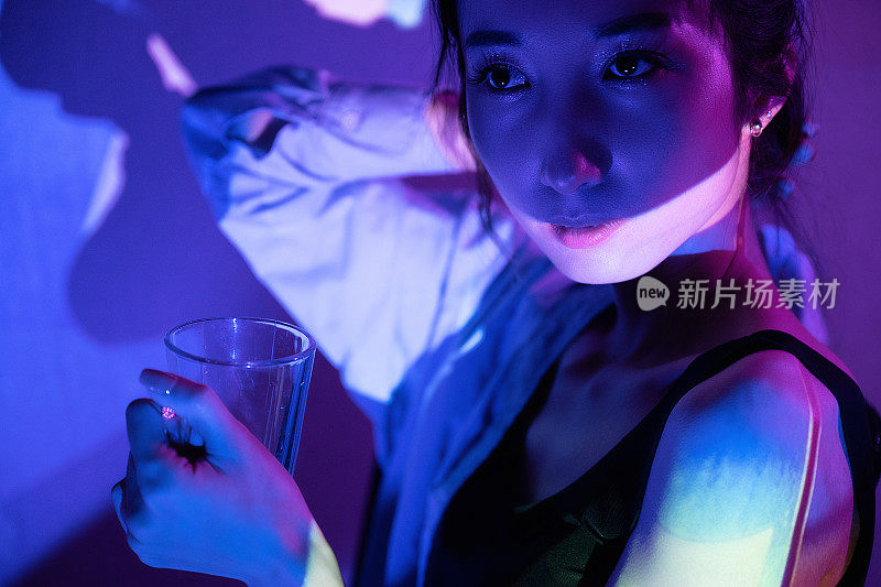 霓虹灯照在拿着透明眼镜的美女身上