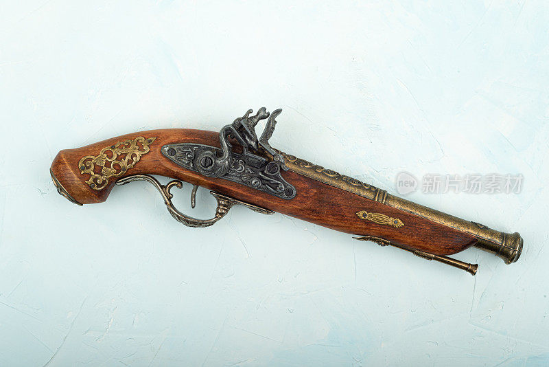一个老式单发手枪的特写镜头，木制背景上有一个敲击锁。