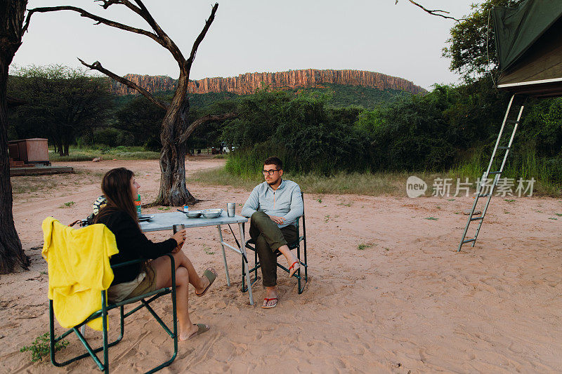 女人和男人旅行者考虑日落露营在纳米比亚的山景