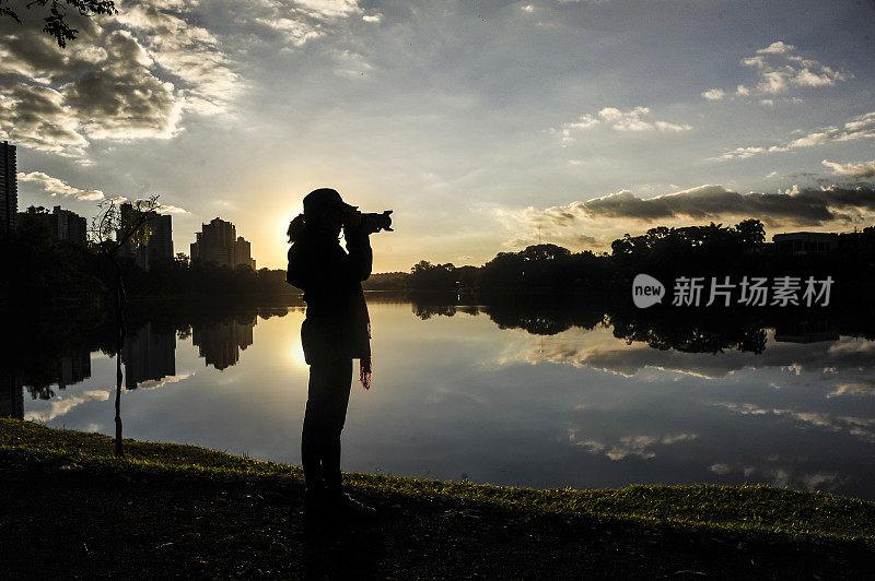 日落时在有湖的公园里拍摄的女人