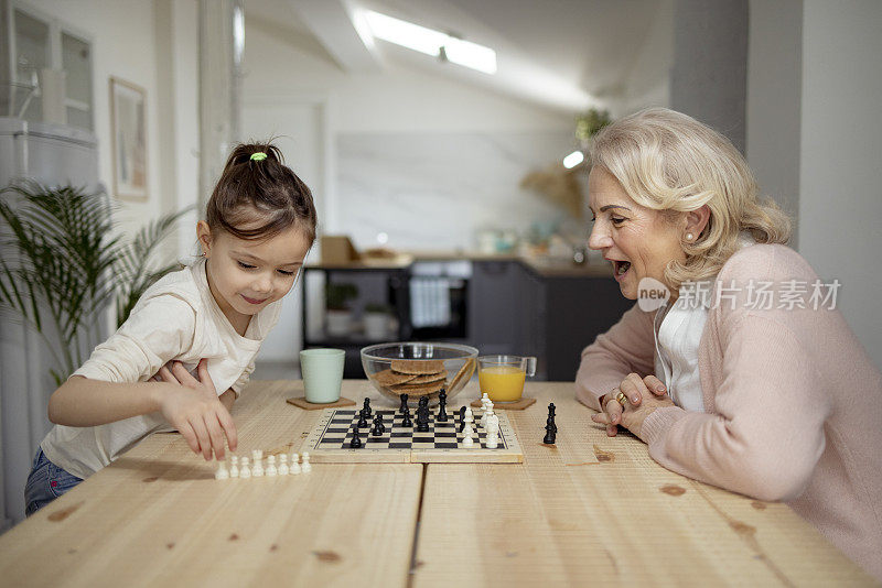 一个白人小女孩和她奶奶在家里下棋