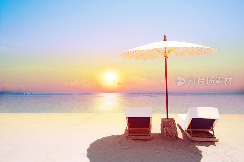 热带海滩日落与沙滩椅和伞